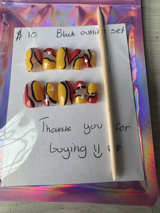 Yellow and red press-on nails with wavy black outlines and white stars
