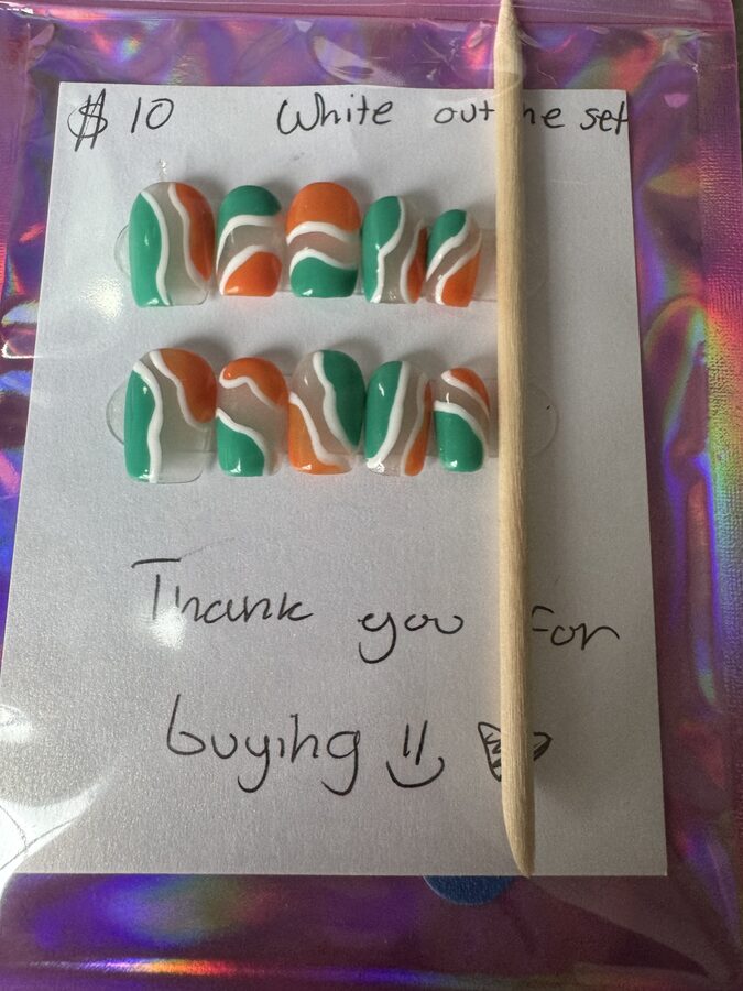 Green and orange press-on nails with wavy white outlines