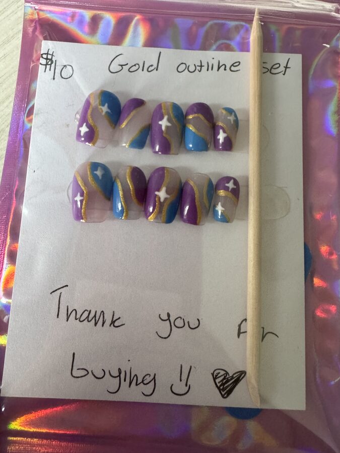 Purple and blue press-on nails with wavy gold outlines and white stars